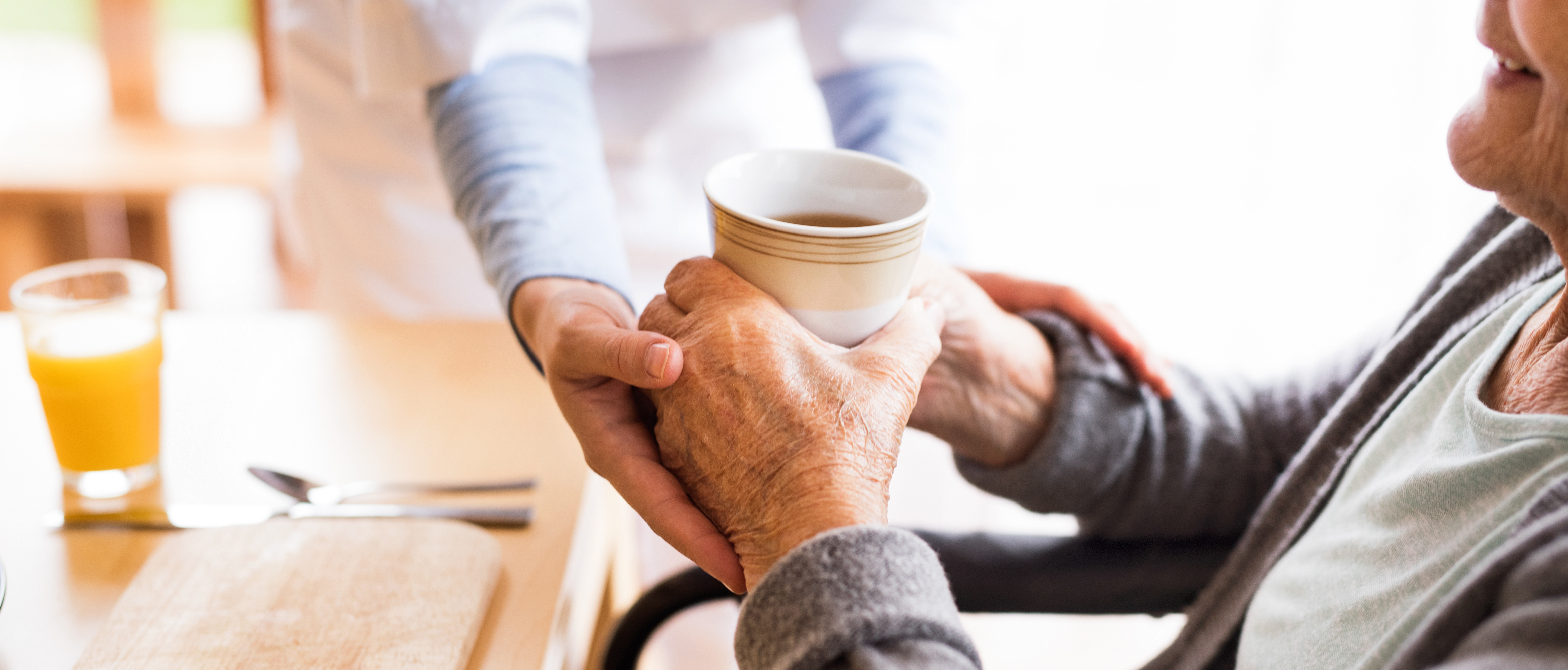 Elder being supported by professional caregiver by providing coffee